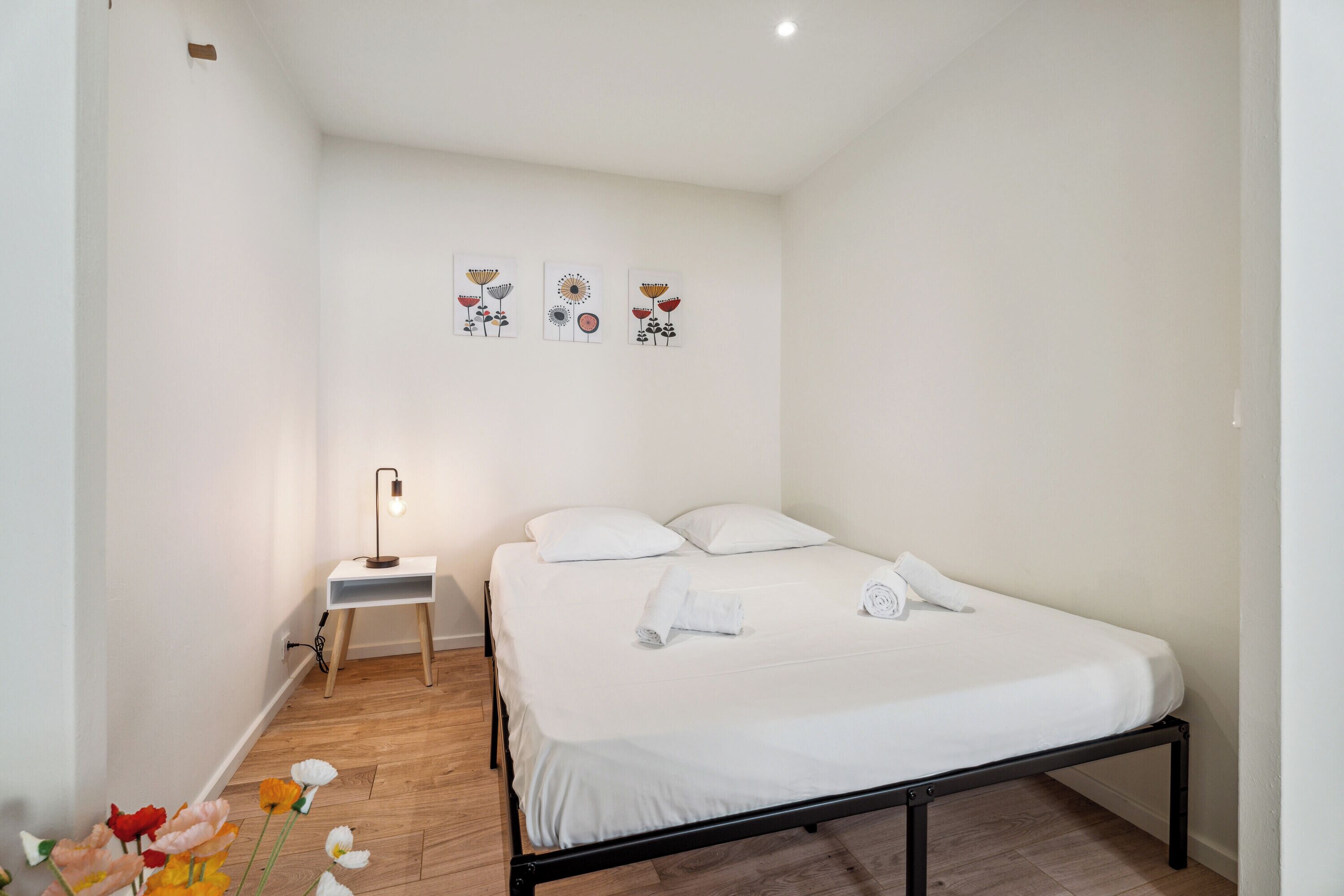 A neatly arranged bedroom with a bed, bedside table, and wall art.