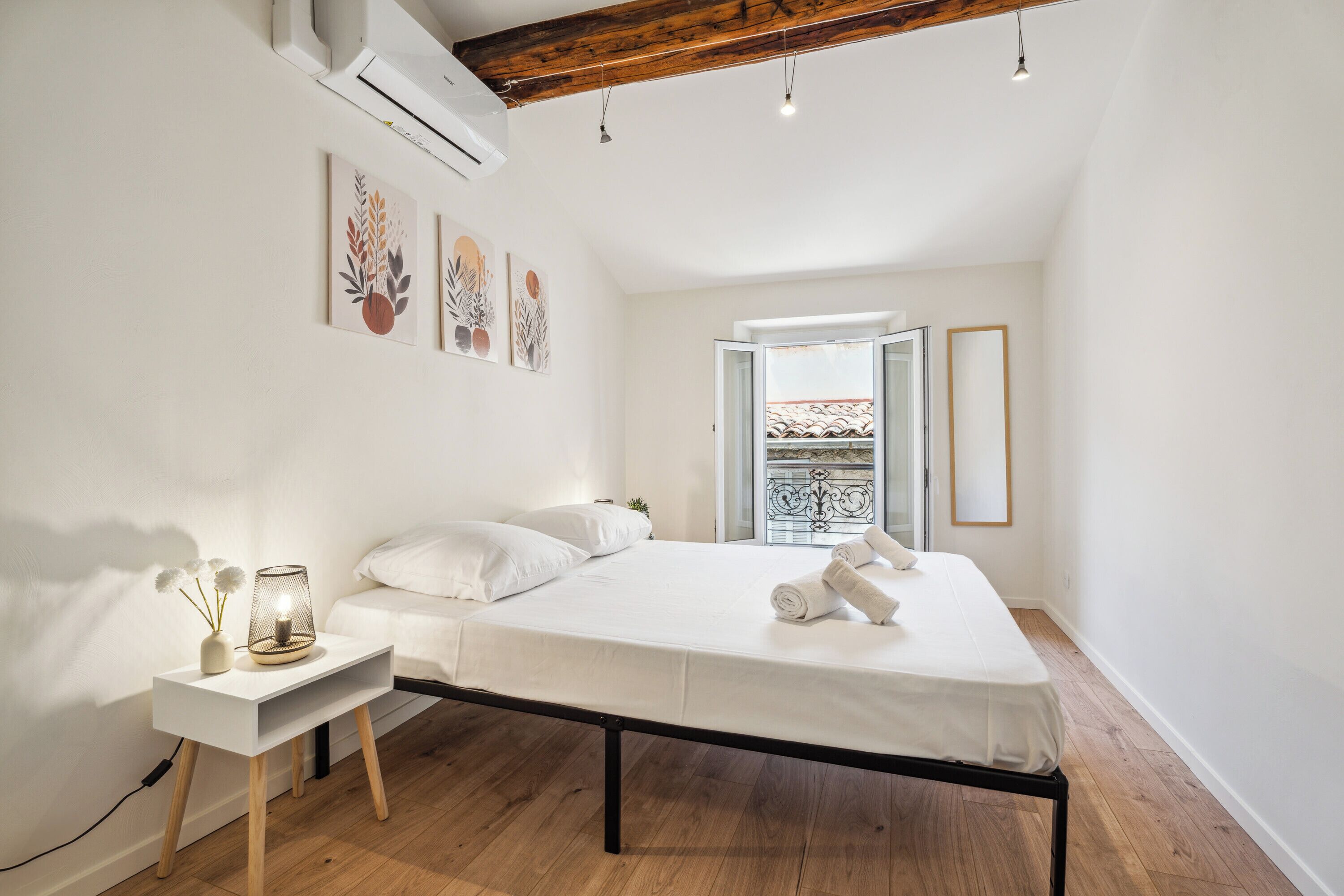 A bedroom with a bed, bedside table, and artwork on the wall.