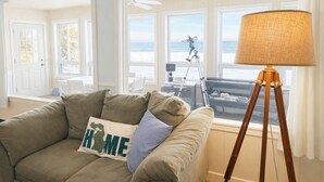 Een woonkamer met een bank, een lamp en uitzicht op het strand.