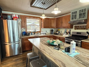 A kitchen with wooden cabinets, stainless steel appliances, a large island, and a window.