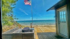 Uitzicht op een strand met een vlag, een houten terras en een gebouw met een deur.