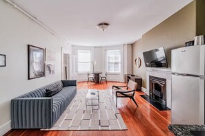 A modern living room with a sofa, a dining table, chairs, a fireplace, and a TV. - Moonlight Beacon Hill Sonata (Boston)