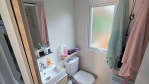 Ein kleines Badezimmer mit Toilette, Waschbecken und Fenster.