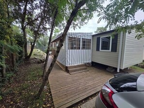 Eine kleine, eingeschossige Holzhütte mit einer Holzterrasse und einer überdachten Veranda.