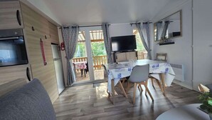 Eine moderne Küche mit Einbauofen, ein Essbereich mit Tisch und Stühlen sowie ein an der Wand montierter Fernseher.