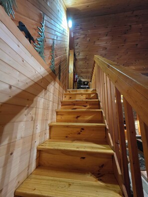 Eine Holztreppe mit einem 'WELCOME'-Schild oben, das zu einer höheren Ebene führt.