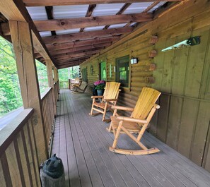 Eine Holzhütte mit Veranda, Schaukelstühlen und Blick auf den Wald.