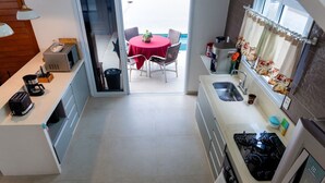 Ett kompakt kök med en matplats, utsikt över havet och ett litet matbord med stolar.