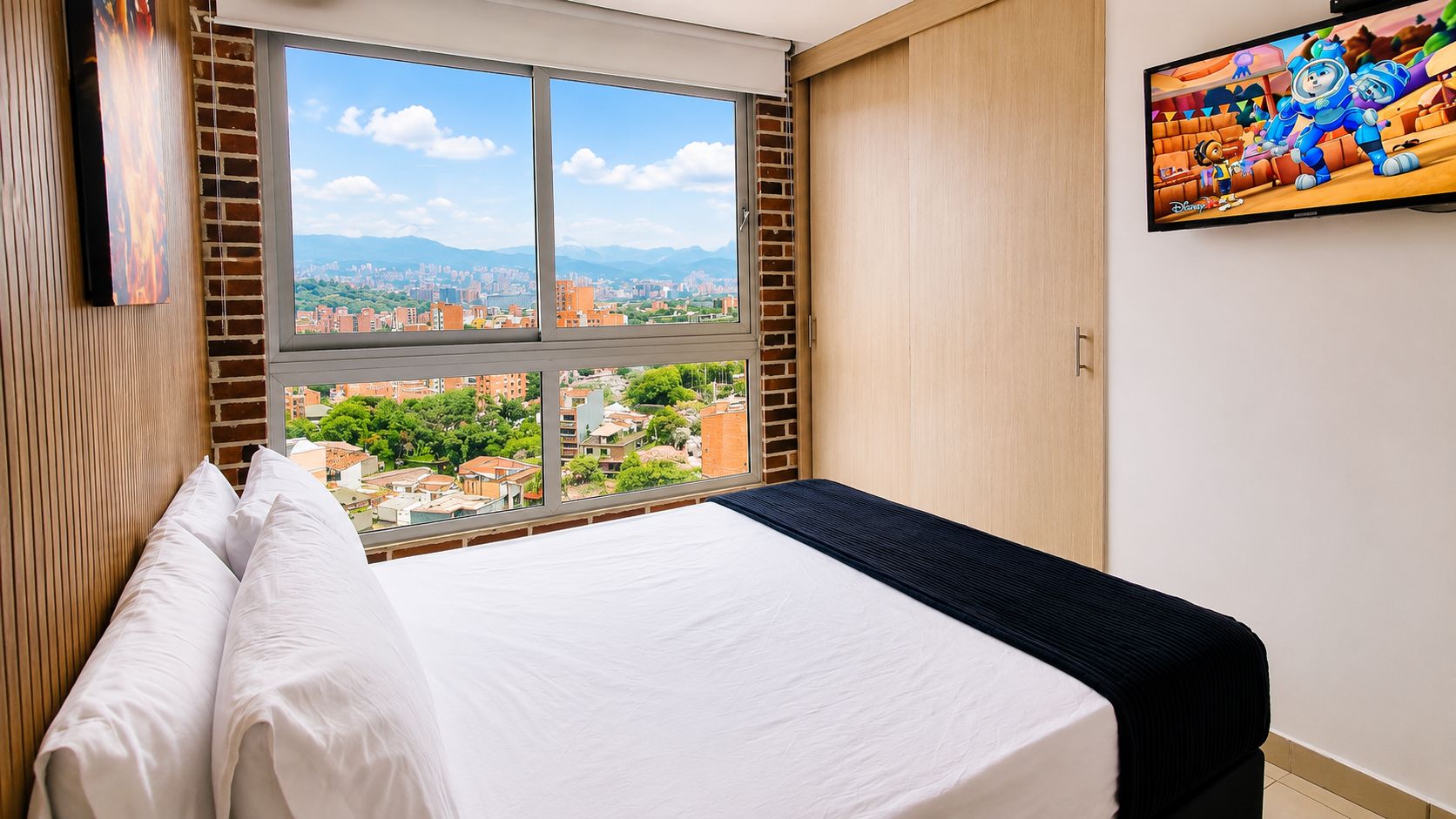 Een slaapkamer met een groot raam, een bed met witte lakens en uitzicht over de stad.