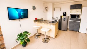 Une cuisine moderne équipée d’un téléviseur à écran plat, d’un évier, d’un réfrigérateur et d’un four à micro-ondes.