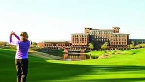Un campo de golf con un edificio grande al fondo.