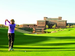 Ein Golfplatz mit einem großen Gebäude im Hintergrund.