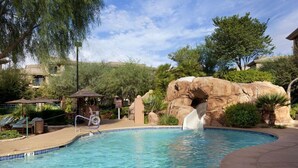 Una piscina con una formación rocosa y una cascada.