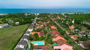 An aerial view of a coastal residential area with houses, a swimming pool, and a view of the ocean. - Casa em Maresias Para 8 Pessoas a 350m da Praia (São Sebastião)