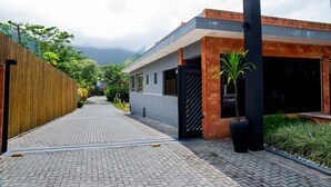 A modern building with a brick facade, a wooden fence, and a paved walkway. - Casa em Maresias Para 8 Pessoas a 350m da Praia (São Sebastião)
