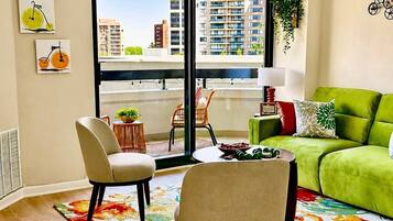 A modern living room with a green sofa, two chairs, a coffee table, and a colorful rug.