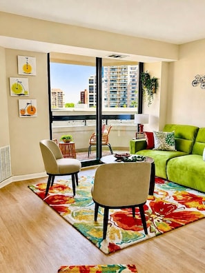 A modern living room with a green sofa, two chairs, a coffee table, and a colorful rug. - New! AMZN HQ-Luxe DCA-Captivating View- DC Airport (Arlington)