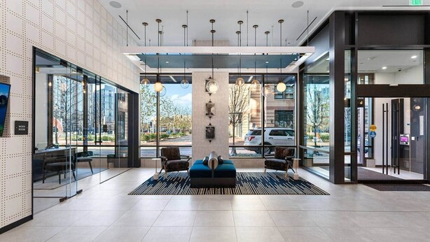 En moderne lobby med receptionsdisk, siddeområde og store vinduer med udsigt til gaden.