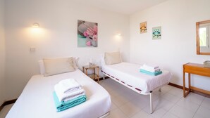 Una camera d'albergo con due letti, un tavolino, uno specchio e decorazioni alle pareti.