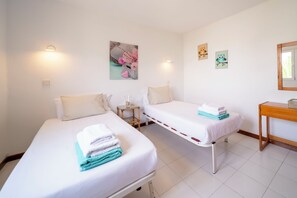 Ein Hotelzimmer mit zwei Betten, einem kleinen Tisch, einem Spiegel und Wandbildern.