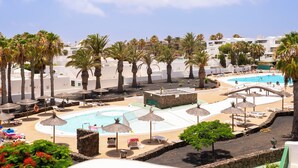 Un resort con area piscina, palme e poltrone da relax.