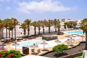 Ein Resort mit Poolbereich, Palmen und Liegestühlen.