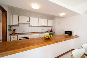 Eine moderne Küche mit weißen Schränken, einer Holz Arbeitsplatte, einer Mikrowelle und einer Obstschale.