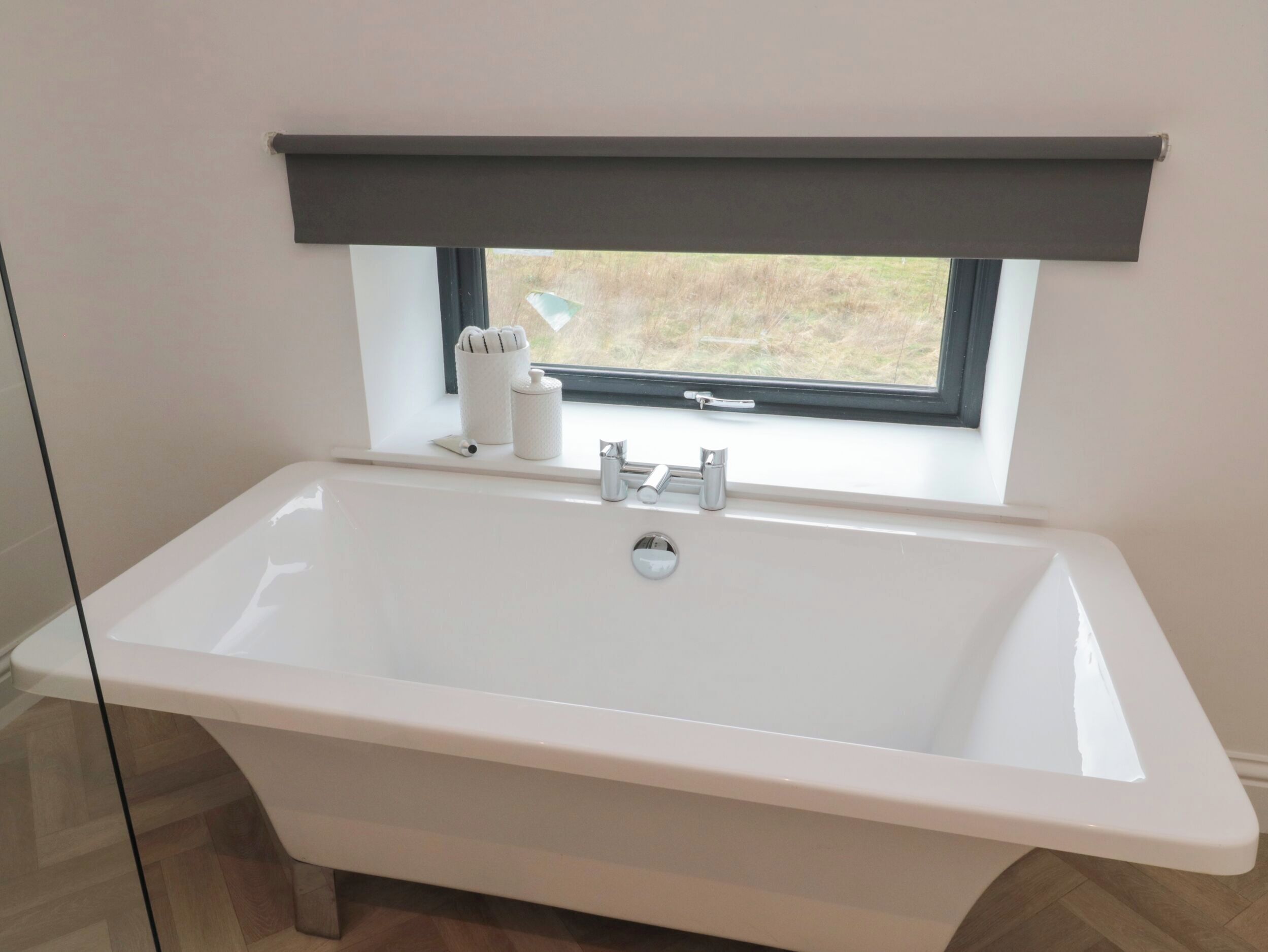 A modern bathroom with a freestanding bathtub, a window with a view, and a towel rack with towels.