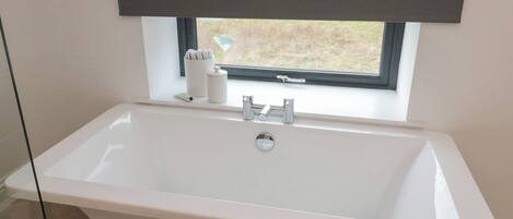 A modern bathroom with a freestanding bathtub, a window with a view, and a towel rack with towels.