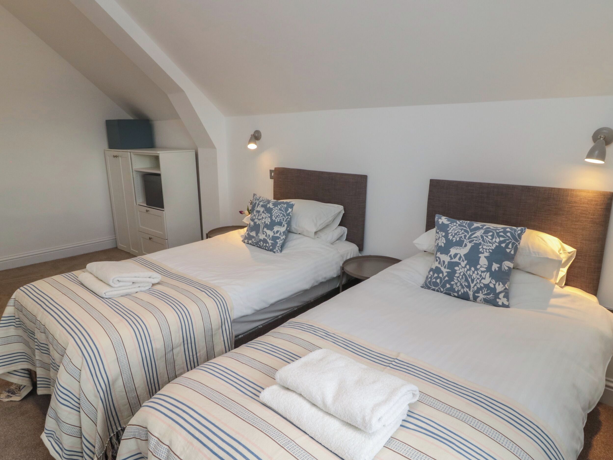 A hotel room with two single beds, a wardrobe, and a small table.