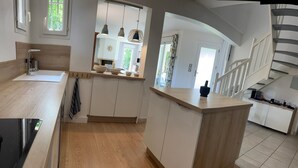 Una cocina moderna con armarios de madera, una isla central y una escalera que lleva a un nivel superior.