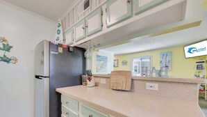 Cocina con refrigerador, encimera con bloque de cuchillos y televisor montado en la pared mostrando 'Big Fish Rentals'.
