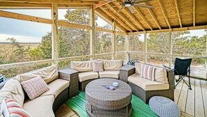Un espace extérieur aménagé, abrité, avec un canapé en osier, une table ronde et un ventilateur de plafond.
