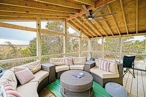 A covered outdoor seating area with a wicker sofa, a round table, and a ceiling fan. - Pets Welcome! Modern Cottage + Screened-In Deck, Steps from the Beach (Milford)