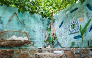 A stone wall with a woven basket, a small plant, and a tiled decoration.