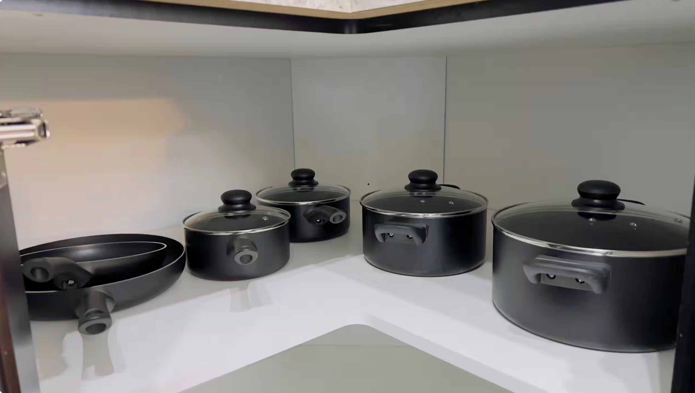 Une cuisine avec quatre casseroles et une poêle sur un plan de travail blanc.