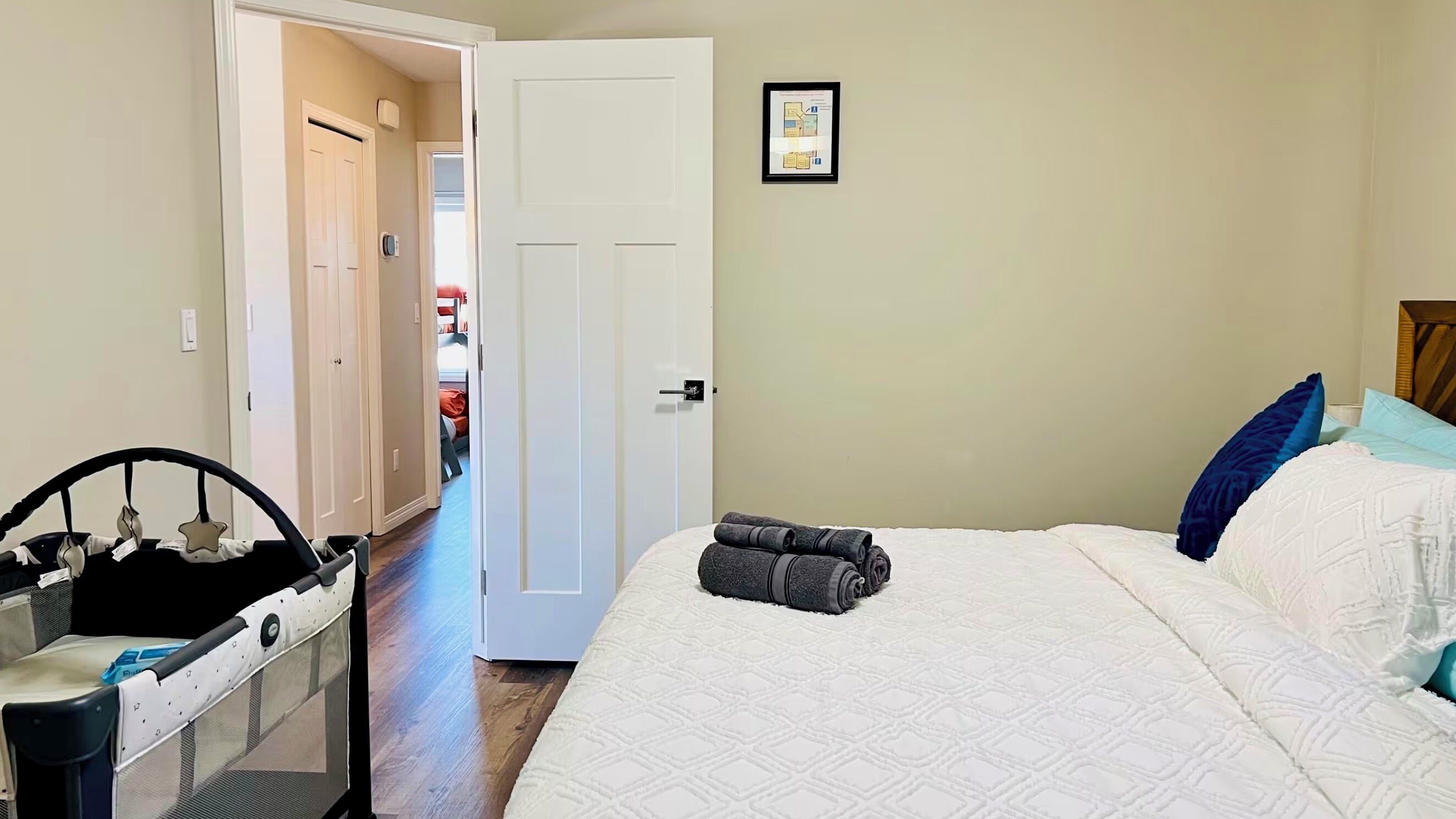 Un dormitorio con cama, cuna, una puerta y un pasillo.
