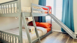 Un letto a castello con una scala, una finestra con tende e un pavimento in legno.