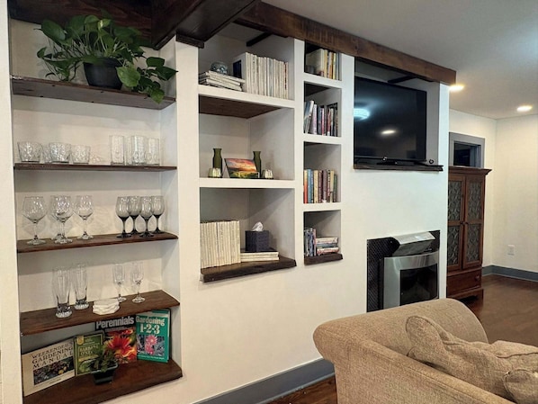 A living room with a fireplace, bookshelves, a television, and a sofa.