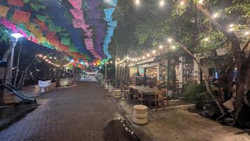 An outdoor dining area with brick flooring, tables, chairs, and string lights.