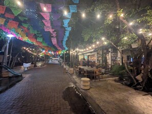 Ein Essbereich im Freien mit Backsteinböden, Tischen, Stühlen und Lichterketten.