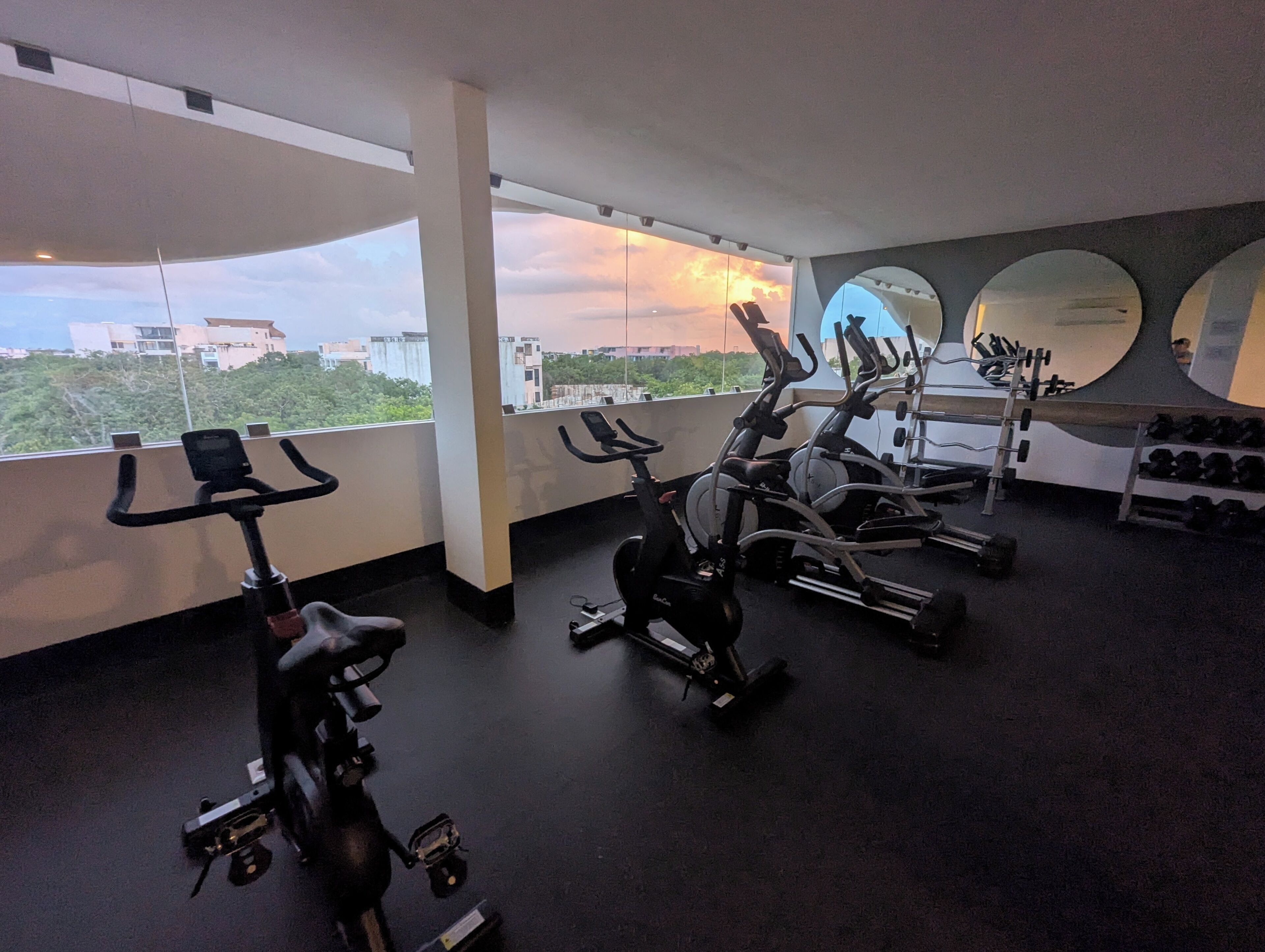 A gym with stationary bikes, elliptical machines, and dumbbells.