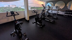 Un gimnasio con bicicletas estáticas, máquinas elípticas y mancuernas.