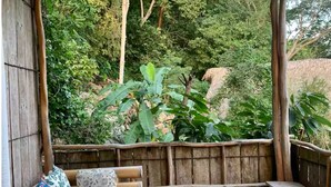 A covered seating area with a bench and cushions, surrounded by a bamboo fence, overlooking a lush garden. - Vereda Yelapa : Abiu (Yelapa)