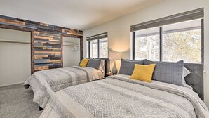 Un dormitorio con dos camas, una pared de acento de madera, una ventana con vistas y una lámpara de noche.