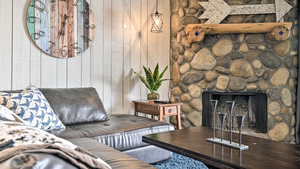 Un salón acogedor con una pared de piedra, un sofá de cuero, una mesa de centro y una chimenea.