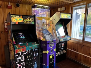 Arcade machines in a wooden room with a window.