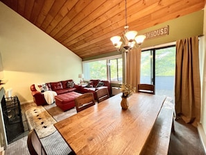 A cozy living room with a red sofa, wooden dining table, and a chandelier.