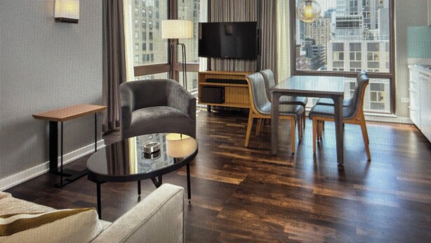 A modern hotel room with a flat-screen TV, a dining table with chairs, a sofa, a small side table, and a large window offering a city view. - Cozy 1-bedroom condo with AC in peaceful New York.  For World Cup Soccer!! (New York)