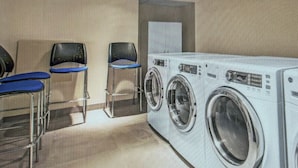 A laundry room with a front-loading washing machine, two chairs, and a table. - Cozy 1-bedroom condo with AC in peaceful New York.  For World Cup Soccer!! (New York)